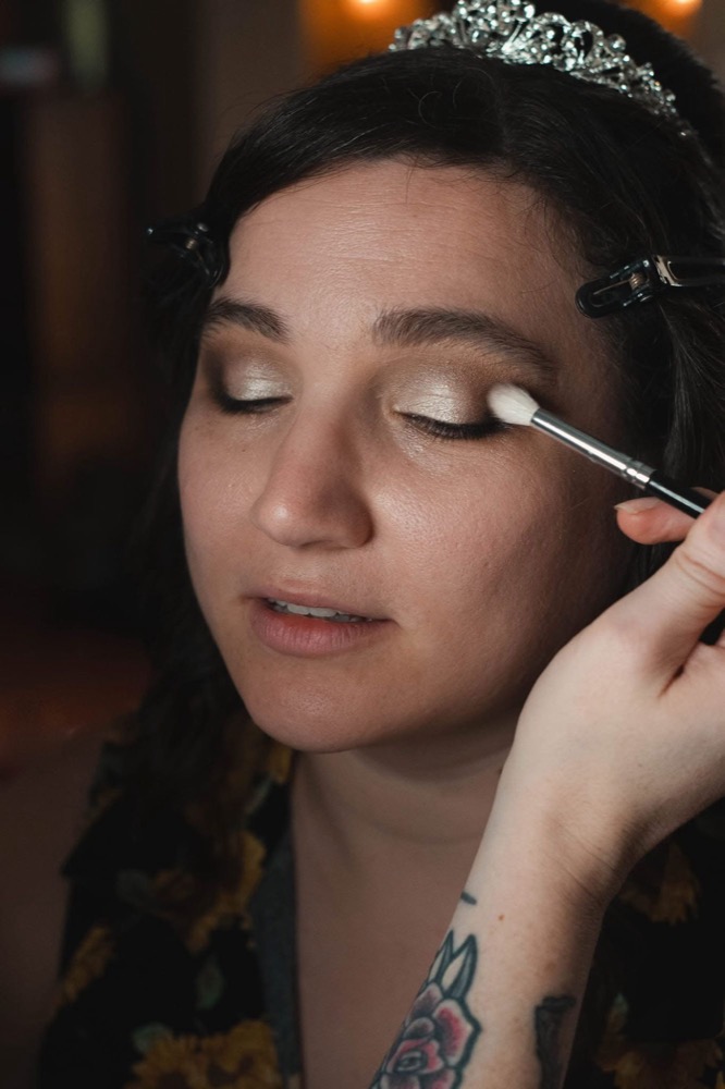 Soft champagne shimmer eye being applied to a bride wearing a tiara